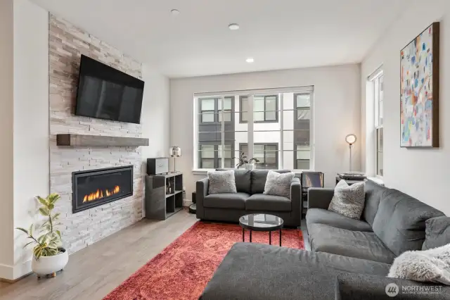 A wall of windows floods the living room with natural light while the fireplace provides warmth.