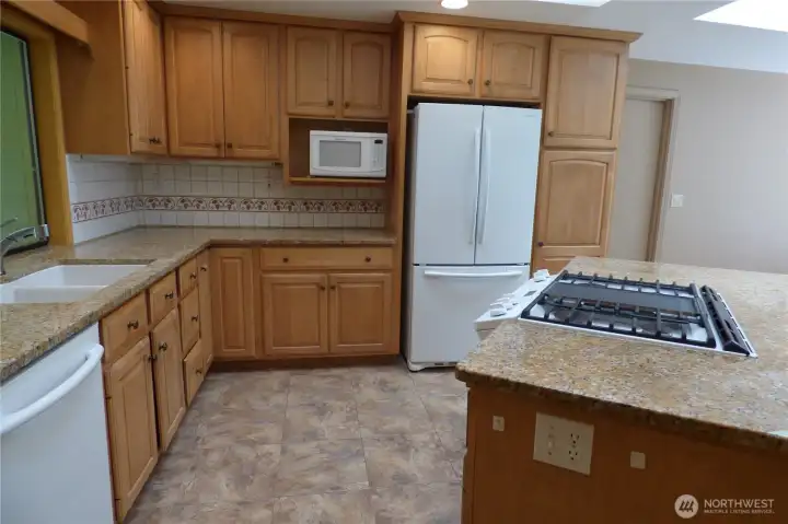 Kitchen with granite counters and gas stove. Ceramic tile flooring in great room.