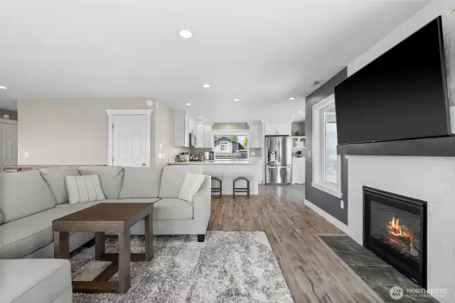 Living room with fireplace opens to dining and kitchen