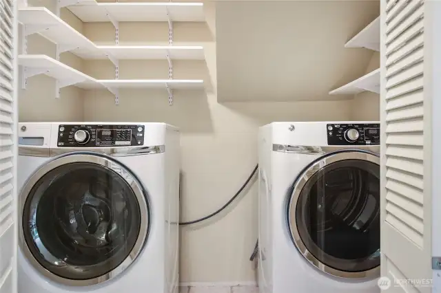 The laundry area offers plenty of shelving. Washer and dryer remain with the home.
