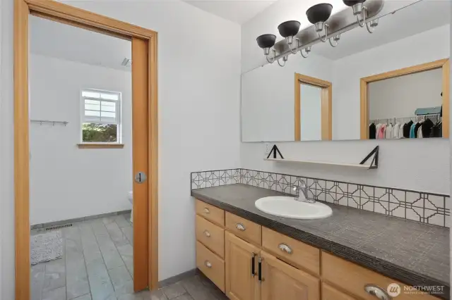 Pocket door separates the shower area and toilet from 2 vanities.
