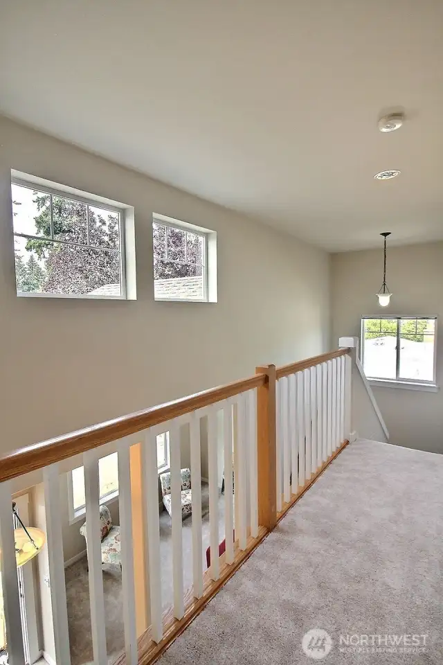 Love this impressive view from the landing on the upper floor showcasing the railing and more magnificent windows! The staircase features lighted stairs too!