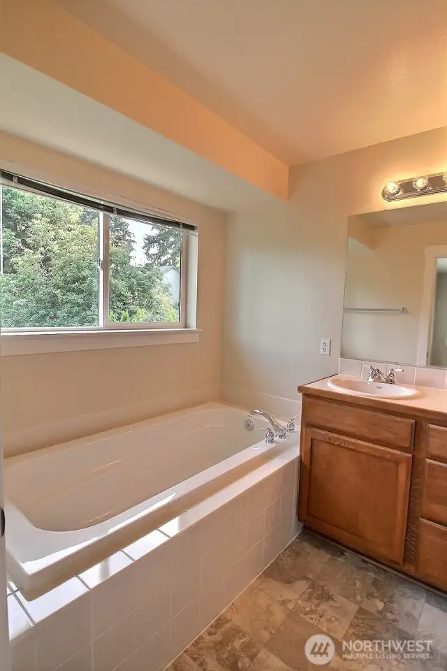 Spa-like primary 5-piece bath offers a large tub with tile surround.