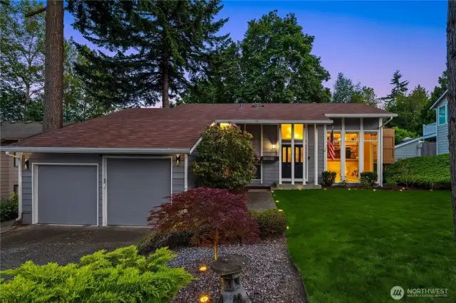 A wide driveway leads to a spacious two-car garage, while thoughtfully placed shrubs and seasonal blooms add warmth and character. The home's modern yet welcoming facade is bathed in natural light, setting the tone for the comfort and style that await inside....