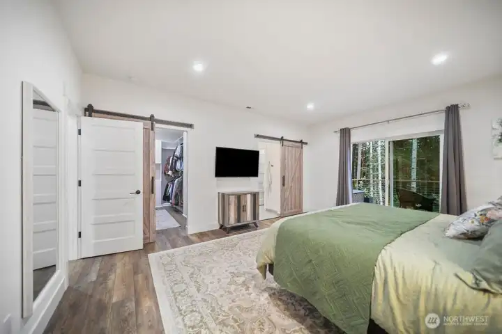 Barn Doors for both the closet and the bath .  Another view of the Primary Bedroom shows the lighting, deck access, and luxury flooring!