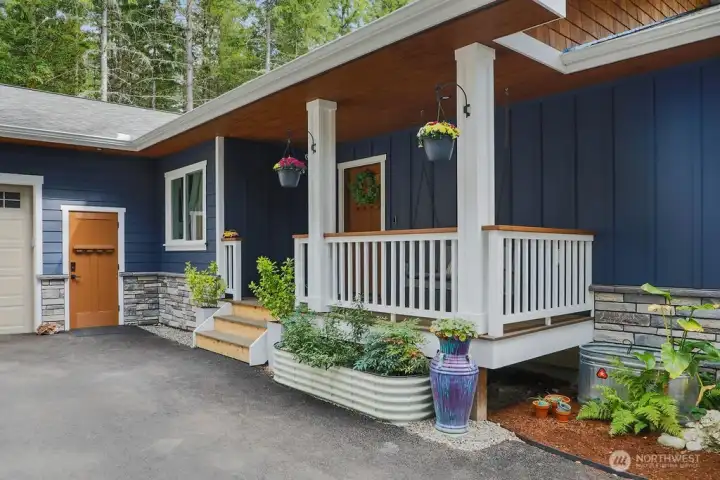 Inviting covered porch with a swing (stays with home)  Catch the sunset colors peeking thru the woods!  The front porch has a Ring camera and owners are leaving. The man door leads to the garage and it is spotless!