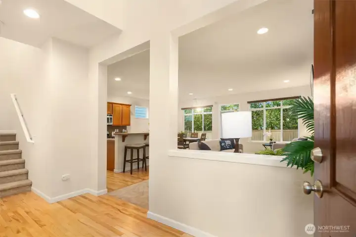 Two story entrance with hardwood flooring and peek-a-boo view into the great room/kitchen area.