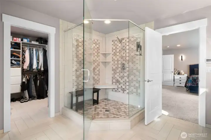 Luxury primary bath featuring a large walk-in shower, open layout, and walk in closet.