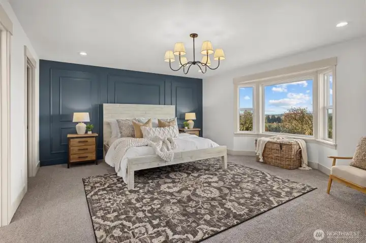 Main floor primary suite with bay window, custom accent wall, elegant chandelier and recessed lighting.
