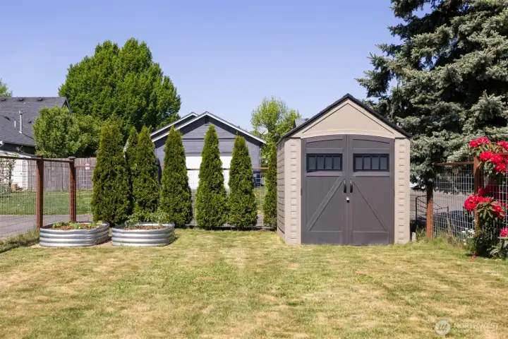Fully fenced backyard with raised garden beds and shed