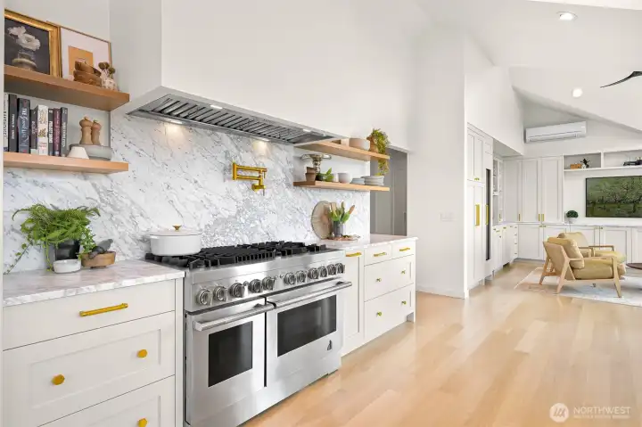 Quartz countertops and a matching quartz backsplash create a sleek, modern aesthetic while offering durability for any culinary adventure. A custom range hood adds both style and function, perfectly complementing the Jenn Air commercial-grade appliances. The thoughtful design continues with a pot filler conveniently positioned above the range, merging practicality with elegance.