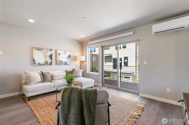 Staged photo of like unit. Living area with view of slider to spacious deck. These units are flooded with natural light!