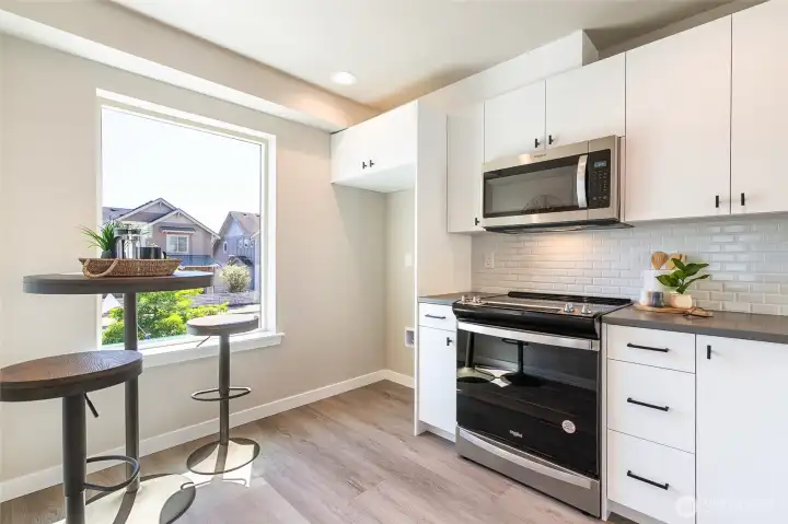 Staged photo of like unit. Stainless appliance with solid surface counters throughout