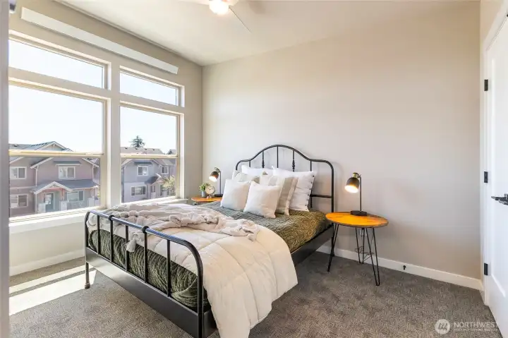 Staged photo of like unit. Main bedroom with large transom windows and ceiling fan with French door closet