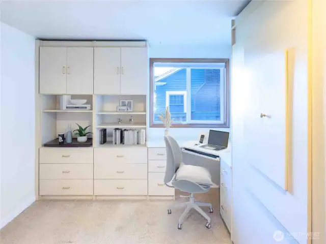 Enjoy this bright and functional second bedroom with built-in shelving, a desk, and a space-saving Murphy bed