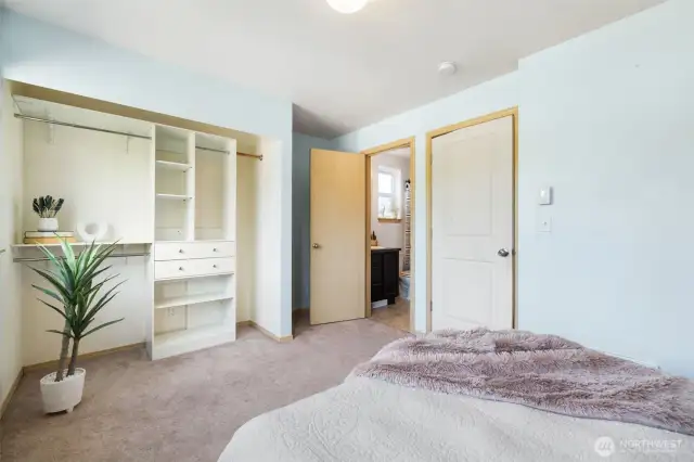 Spacious primary bedroom with shelving unit and attached bathroom.