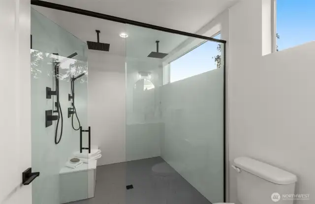 Rainfall luxury, daily — Your private spa awaits—featuring a frameless glass shower with double rainfall heads and a window to the sky.