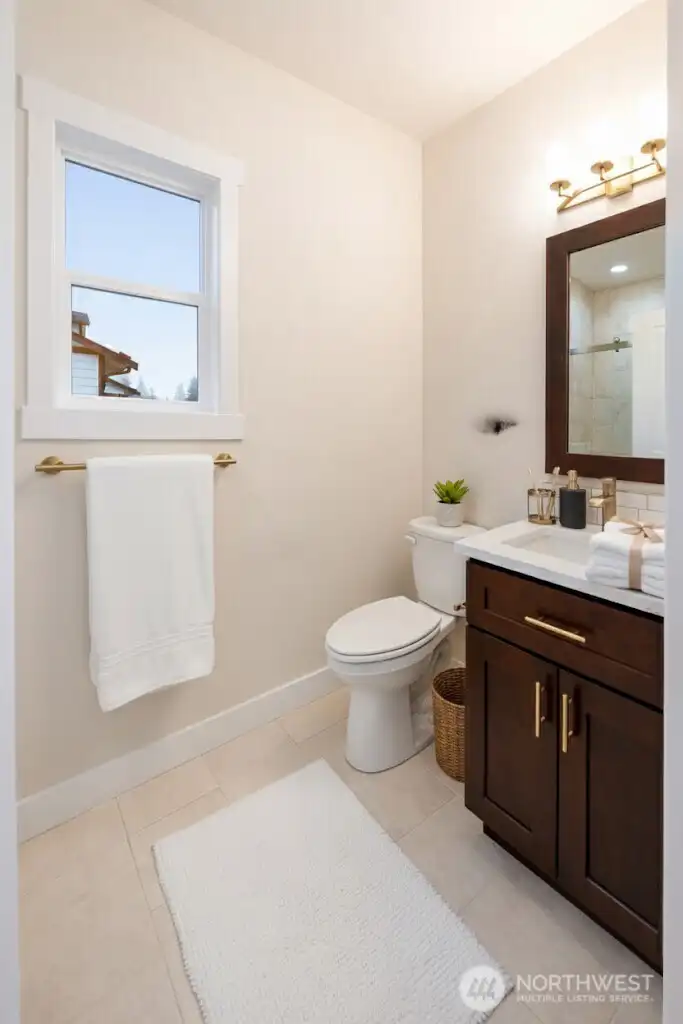 Main floor 3/4 bath with solid quartz shower floor and tile surround. This is a virtually staged photo.