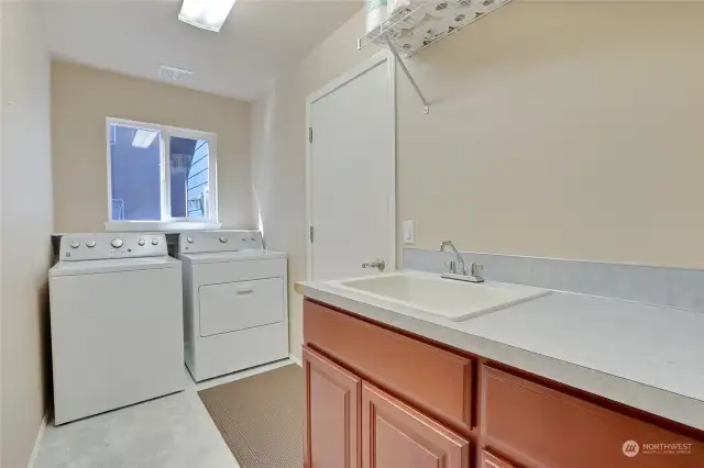 Oversized utility room with sink, cabinet storage and door to garage.