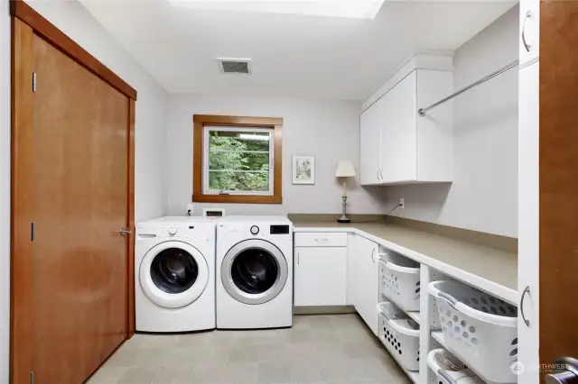 Laundry room has custom built ins for under counter organization and plenty of cabinets for storage