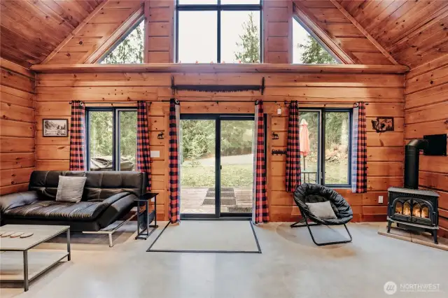 Living room anchored by architectural windows, vaulted ceilings & rustic pine log walls