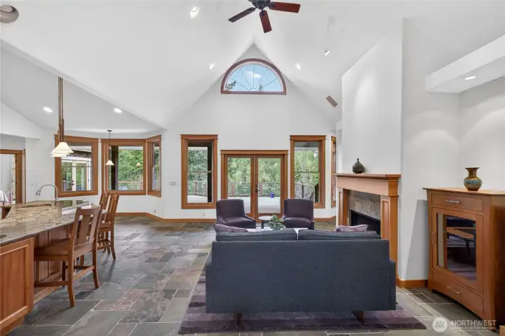 Vaulted ceilings and an open concept for living room and kitchen with eat-in space for a table by the windows on the left.