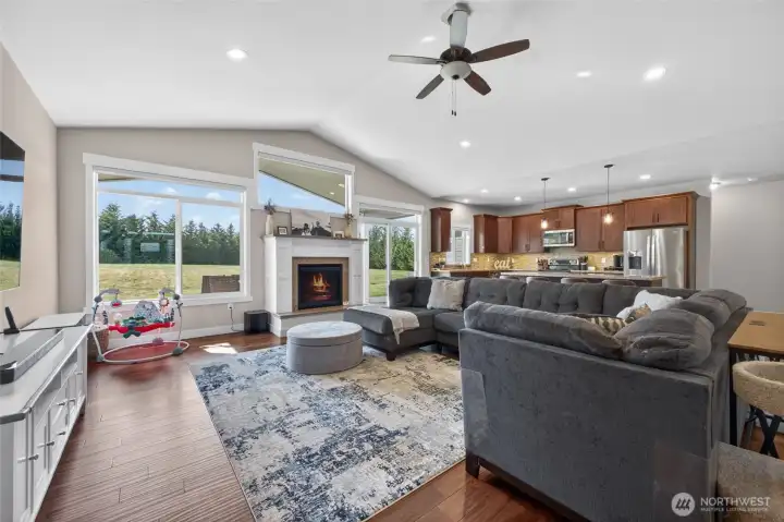 Light-filled living area featuring vaulted ceilings, cozy fireplace, and large windows overlooking the backyard.