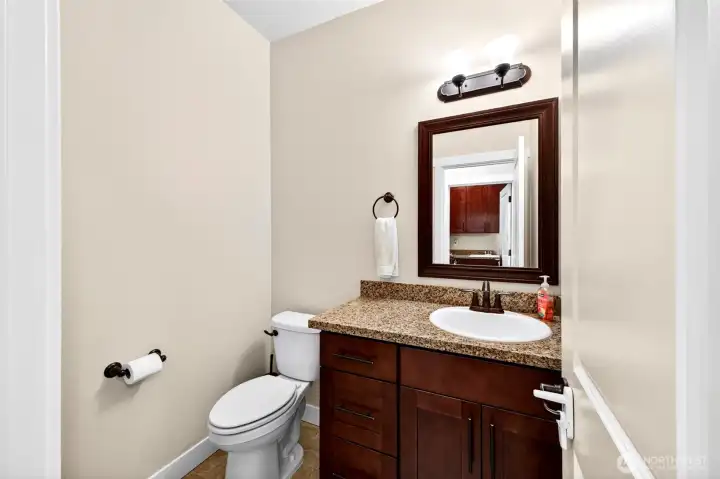 Convenient guest powder room featuring granite countertops and upgraded cabinetry.