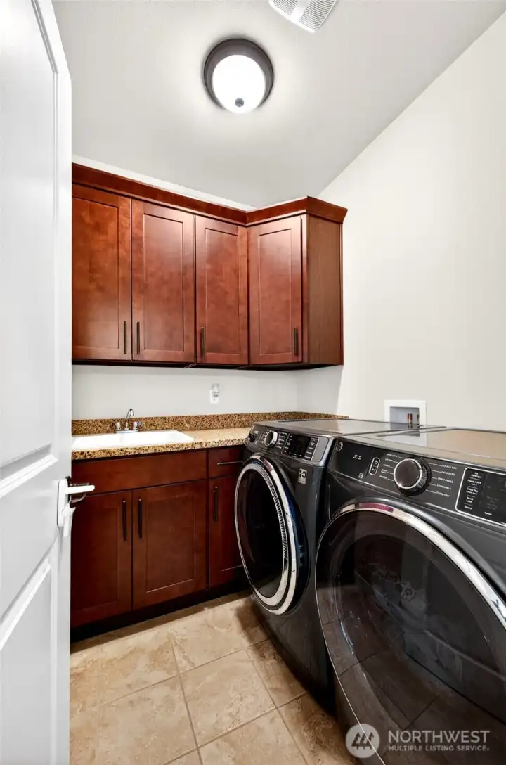 Well-appointed utility room featuring abundant cabinetry, utility sink, and extra storage to keep daily life organized.