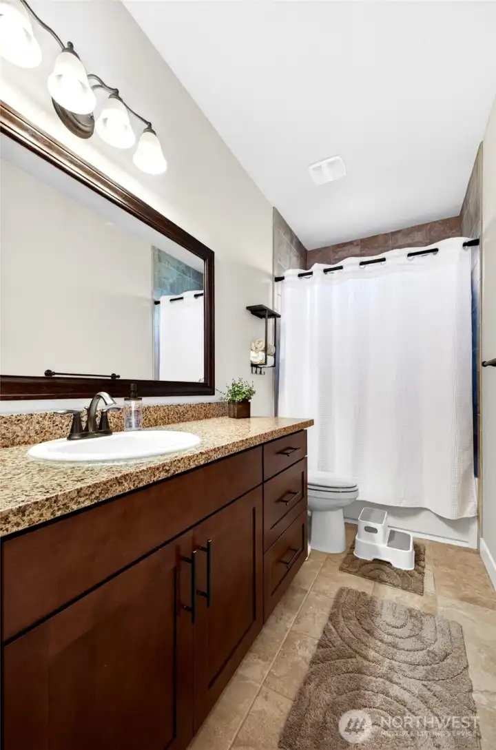 Full guest bath with granite countertops, quality cabinetry, and convenient access to secondary bedrooms.