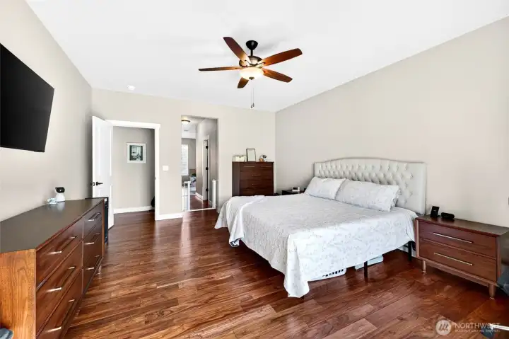 Expansive primary suite with rich hardwood flooring, ceiling fan, and plenty of space for a king-size bedroom set.