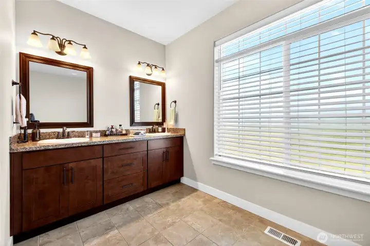 Elegant dual-sink vanity with granite countertops, abundant cabinet storage, and framed mirrors.