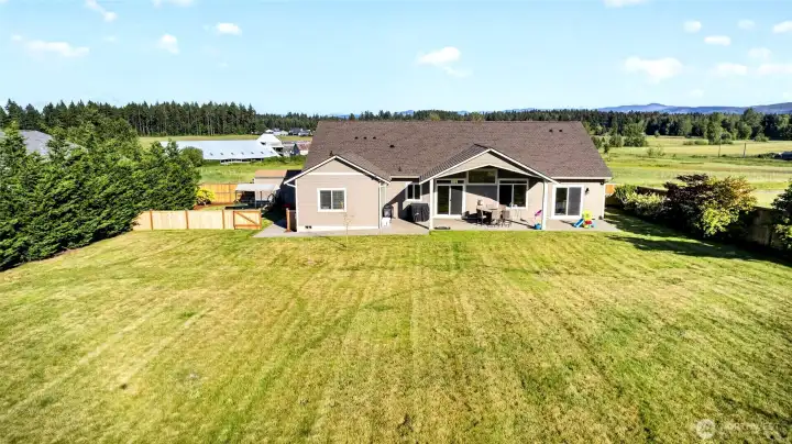 Private, fully fenced backyard with expansive lawn, covered patio, and plenty of room for play, gardening, or gatherings.
