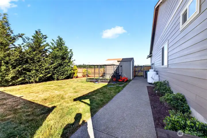 Wide side yard with gated access, storage shed, and additional space for equipment, gardening, and pets.