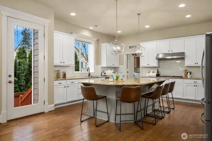 The expansive kitchen is a chef's dream, featuring a wraparound island with seating, premium appliances, crisp white cabinetry, and abundant storage — all bathed in natural light for a bright and highly functional workspace. The expansive kitchen is a chef's dream, featuring a wraparound island with seating, premium appliances, crisp white cabinetry, and abundant storage — all bathed in natural light for a bright and highly functional workspace.