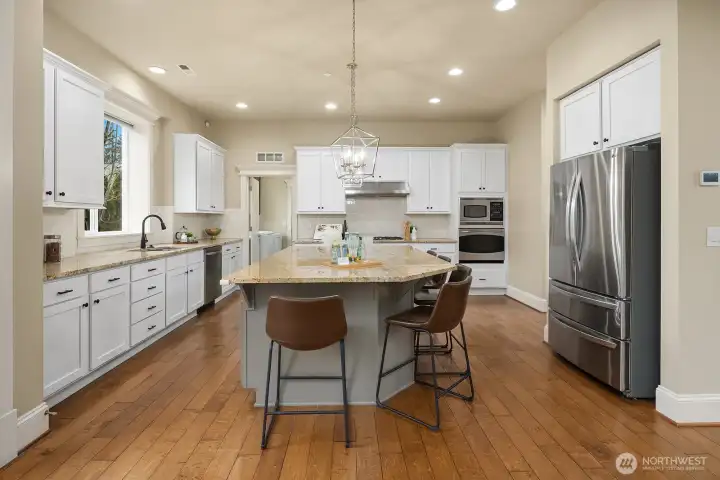 This view of the kitchen highlights the thoughtful layout with ample counter space, high-end stainless steel appliances, and rich hardwood flooring — a polished and practical space at the true heart of the home. This view of the kitchen highlights the thoughtful layout with ample counter space, high-end stainless steel appliances, and rich hardwood flooring — a polished and practical space at the true heart of the home.