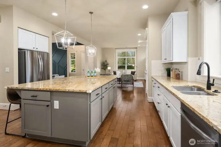 A closer look at the kitchen's wraparound island and farmhouse-style sink highlights the premium finishes and thoughtful design details, with an open sightline into the living areas beyond that makes this space as connected as it is beautiful. A closer look at the kitchen's wraparound island and farmhouse-style sink highlights the premium finishes and thoughtful design details, with an open sightline into the living areas beyond that makes this space as connected as it is beautiful.