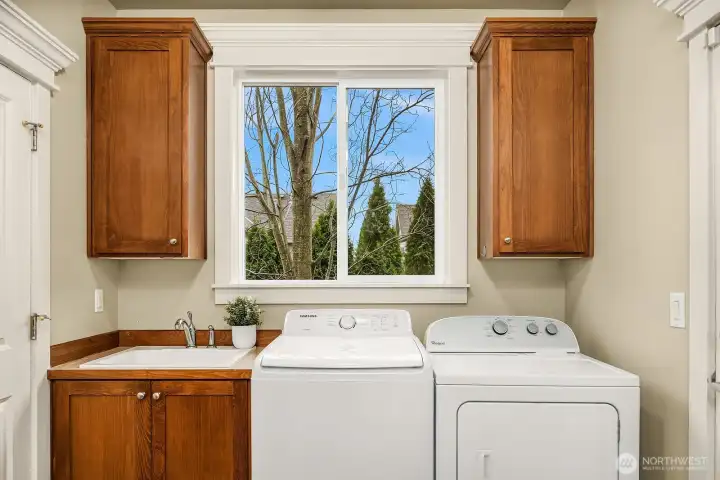 The conveniently located laundry room features a full-size washer and dryer, warm wood cabinetry for ample storage, and a utility sink — a well-appointed and practical space that makes everyday chores a breeze. The conveniently located laundry room features a full-size washer and dryer, warm wood cabinetry for ample storage, and a utility sink — a well-appointed and practical space that makes everyday chores a breeze.