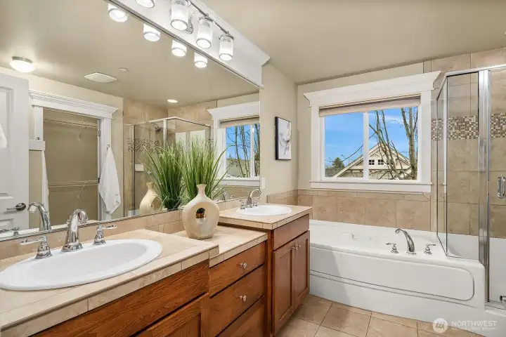 The spa-inspired five-piece primary bath features double vanities, a soaking tub, and warm wood cabinetry — a luxurious and beautifully appointed retreat designed for rest and rejuvenation. The spa-inspired five-piece primary bath features double vanities, a soaking tub, and warm wood cabinetry — a luxurious and beautifully appointed retreat designed for rest and rejuvenation.