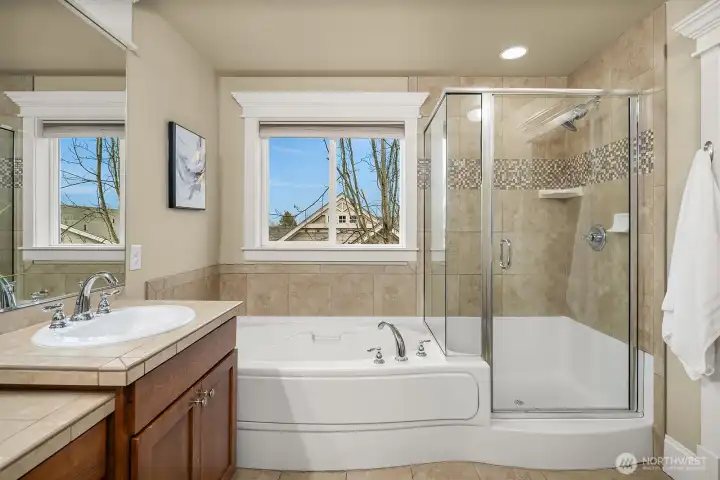 Another angle of the primary bath highlights the elegant soaking tub, glass-enclosed shower, and bright window — a thoughtfully designed and indulgent space that completes this exceptional primary suite. Another angle of the primary bath highlights the elegant soaking tub, glass-enclosed shower, and bright window — a thoughtfully designed and indulgent space that completes this exceptional primary suite.