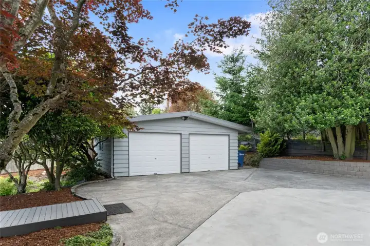 Detached two-car garage with generous driveway parking framed by mature landscaping. Detached two-car garage with generous driveway parking framed by mature landscaping.