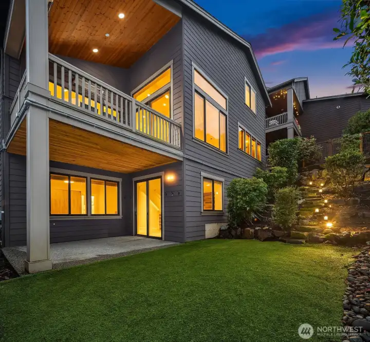 Rear elevation showcases multiple covered outdoor living spaces, professionally landscaped grounds, and seamless indoor-outdoor living.