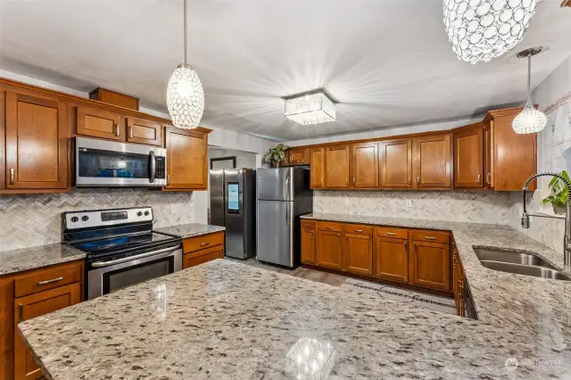 Updated spacious kitchen with quartz countertops and tile backsplash.