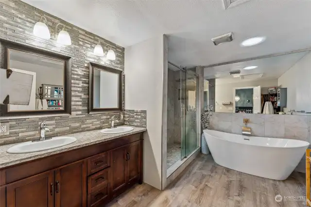 Remodeled 5-piece bath with tile backsplash, quartz countertops, LVP floors and shower with tile surround in the Primary bathroom.