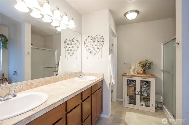 This well-appointed primary ensuite includes dual vanities, a walk-in shower, a deep soaking tub, and a private water closet.