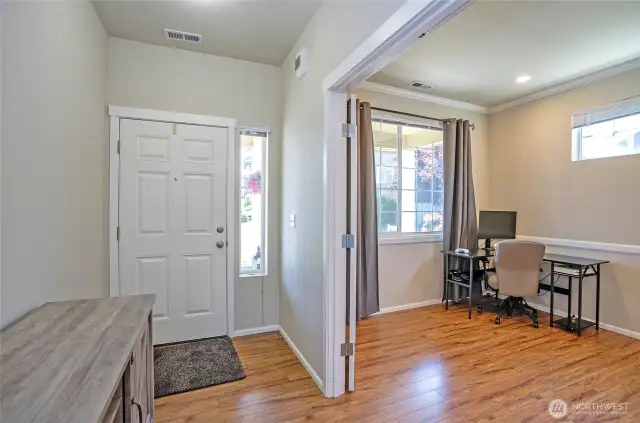 Upon entering the home, you'll find double doors to the right leading to a flexible space—perfect as a home office, den, or relaxing sitting area. Beautiful laminate flooring flows throughout the main level, adding warmth and style.