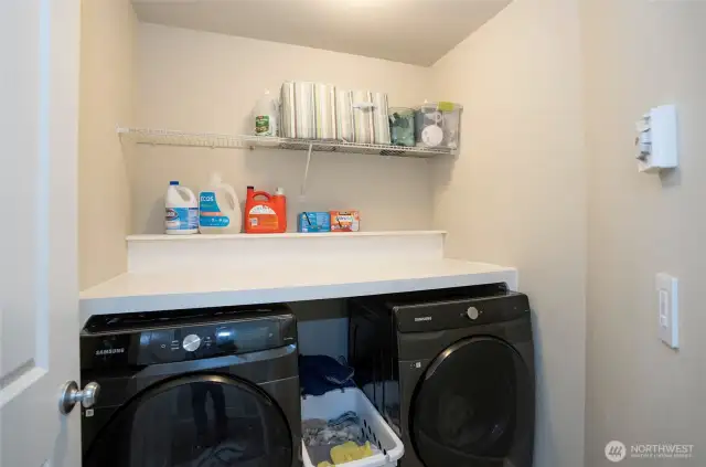 Designed for efficiency, this upper-level laundry room features extra shelving and a spacious folding surface above the washer and dryer.