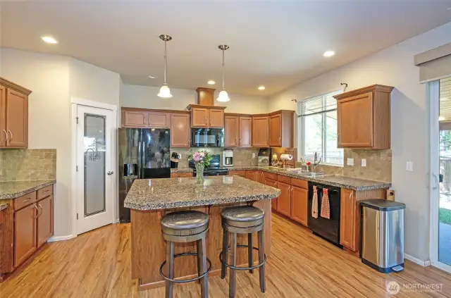The gorgeous island kitchen is highlighted by solid granite counters, rich cabinetry, a quick dining bar, and plenty of room for culinary creativity.