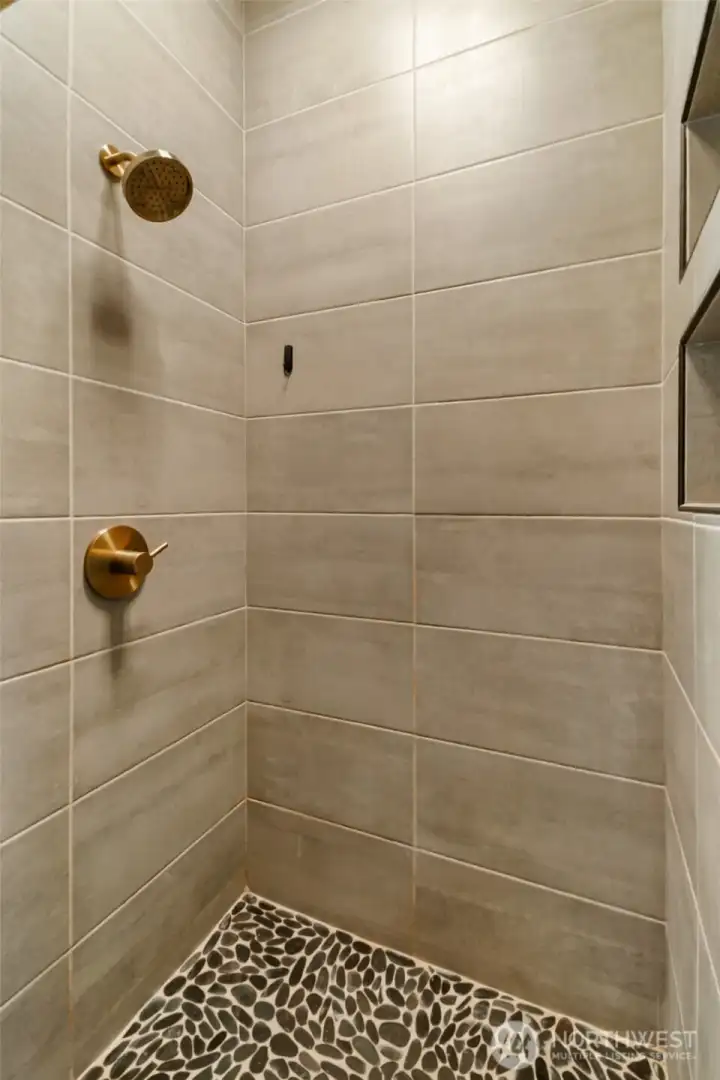 Fully tiled shower w/2 niches with natural stone accents