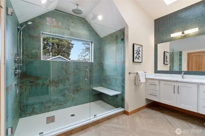 Incredible ensuite bath with custom tile, vaulted shower ceilings, and window showcasing the surrounding trees.
